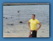 Eric on the beach with a Brown Pelican in flight behind him.